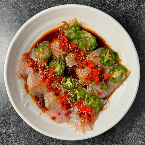 Banzai Sushi's yellowtail sashimi with jalapeños, red roe, sesame seeds, and soy sauce.