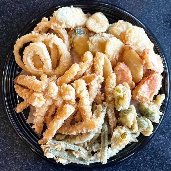 A large platter of assorted Japanese tempura, including shrimp, vegetables, and onion rings.