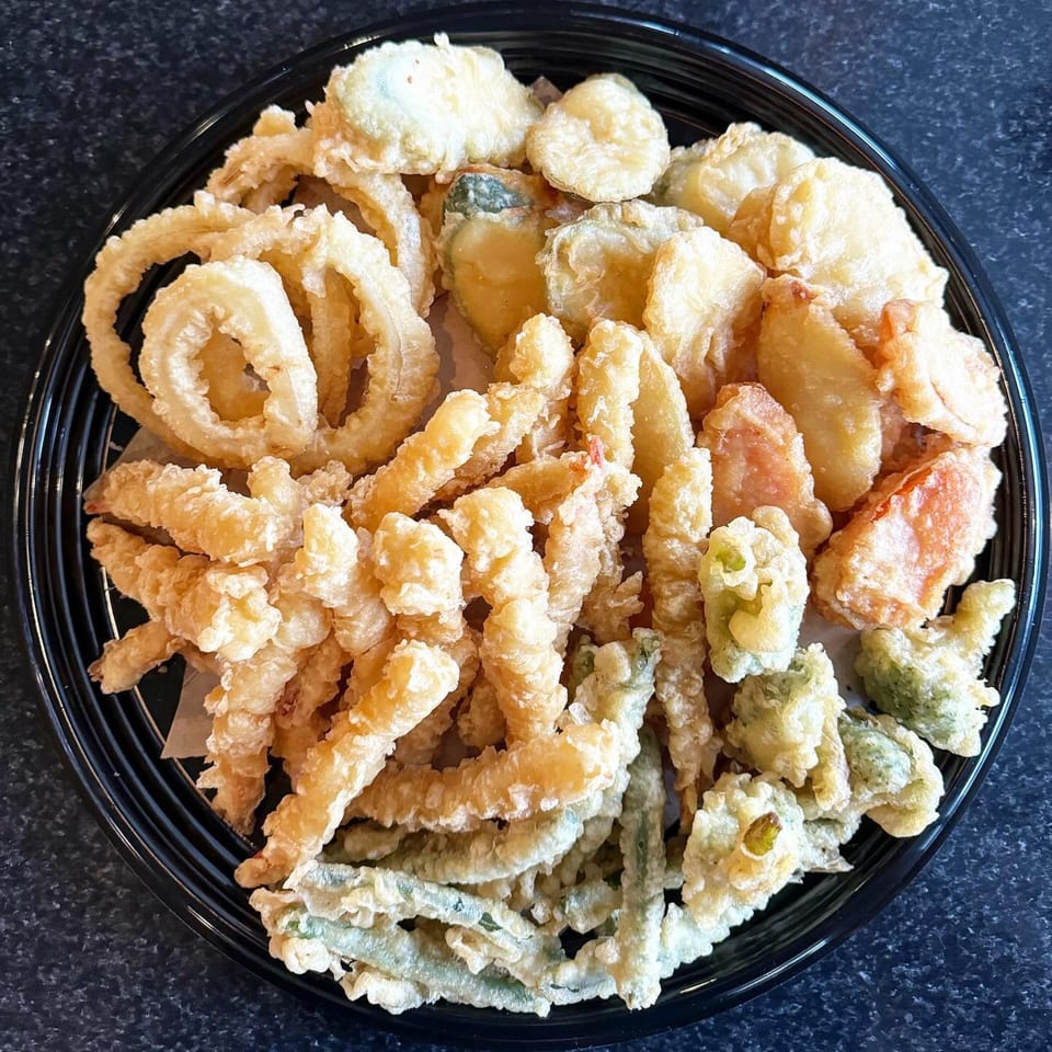 A large platter of assorted Japanese tempura, including shrimp, vegetables, and onion rings.