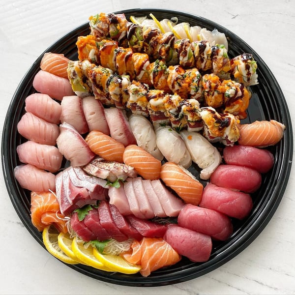 A large black platter filled with various Banzai Sushi rolls, nigiri, and sashimi.