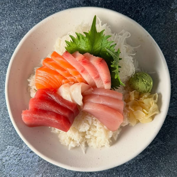 A Banzai Sushi chirashi bowl with various sashimi over rice, garnished with wasabi and ginger.